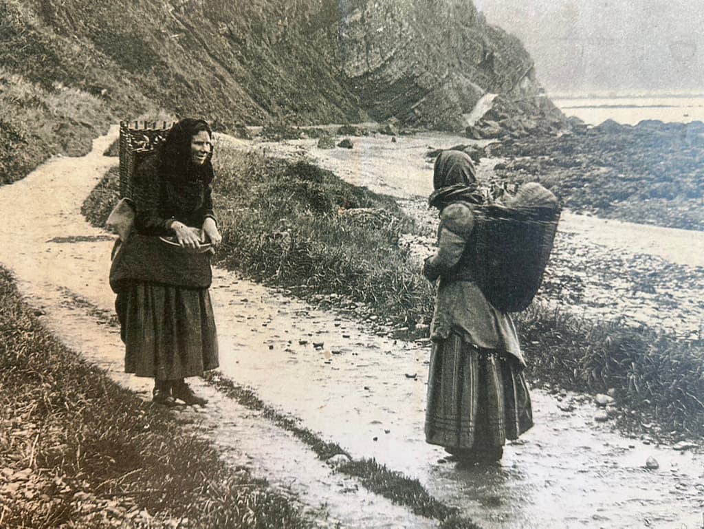 Fisherwomen carrying creels along the shore path, historic photo