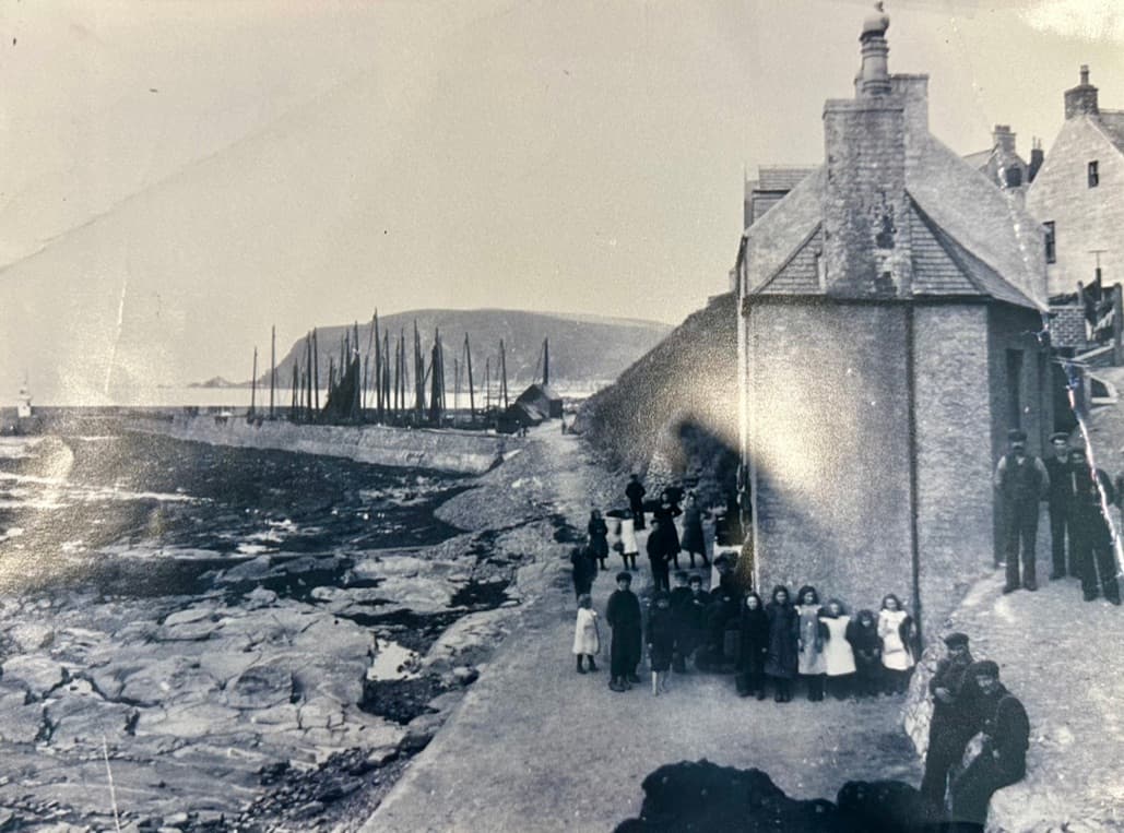 Villagers gathered by the harbour wall, historic photo