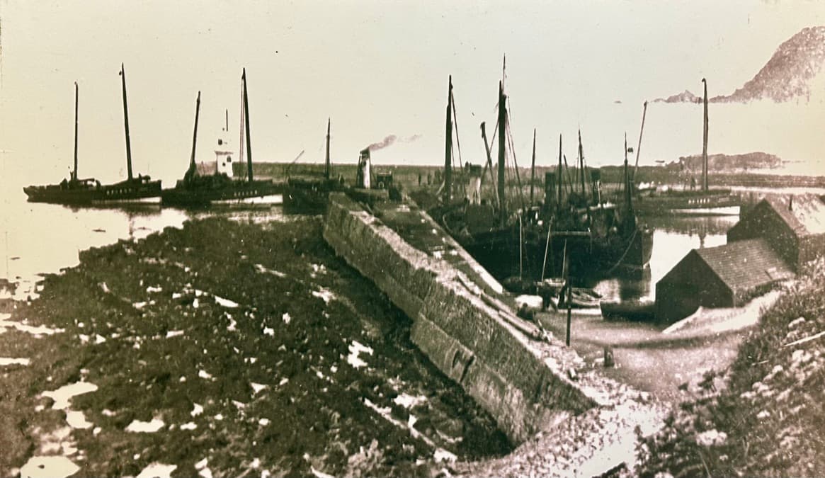 Boats moored either side of the harbour breakwater, historic photo