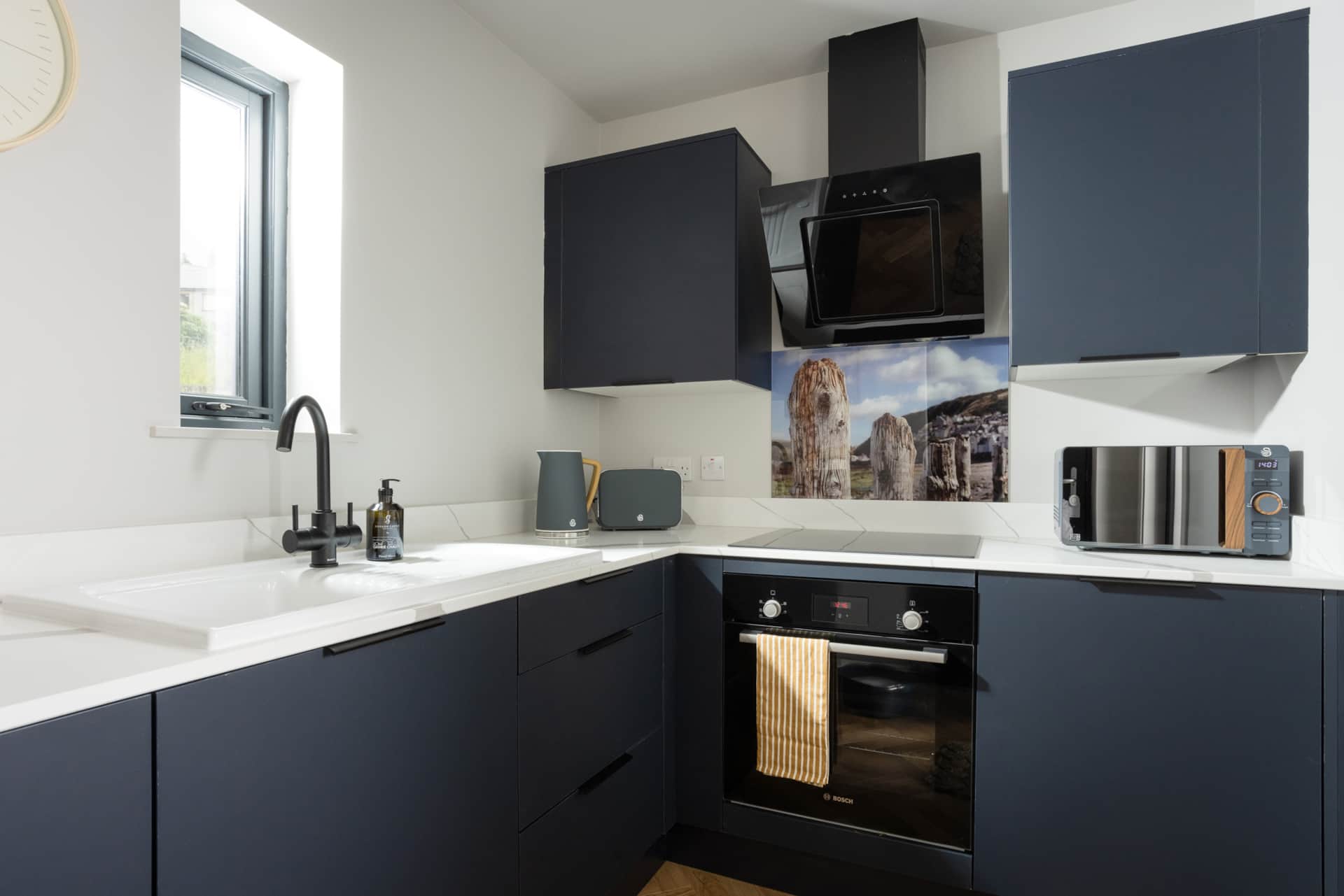 Navy kitchen with oven, hob, and sea-view splashback