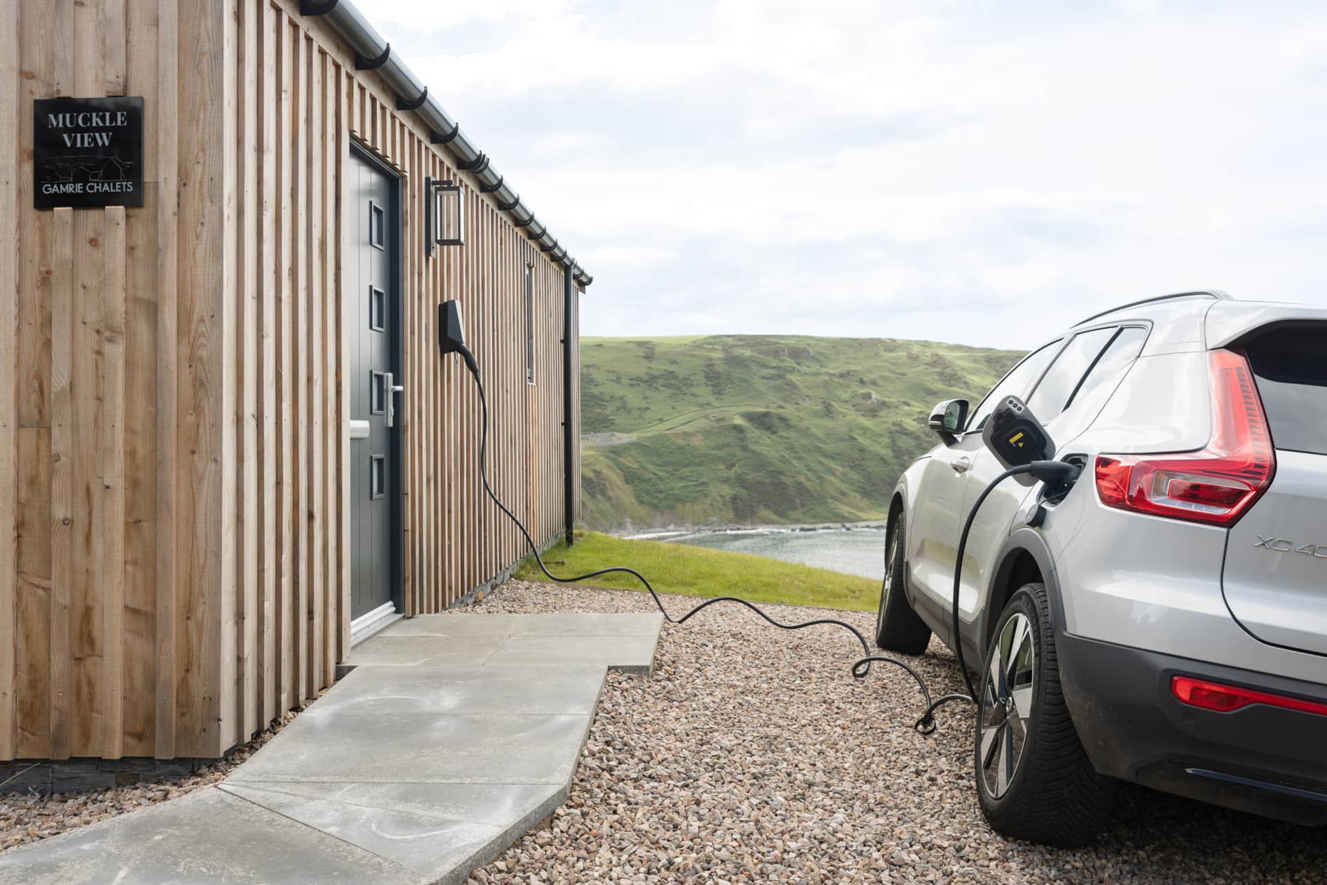 Electric car charging by the front door, with the bay beyond
