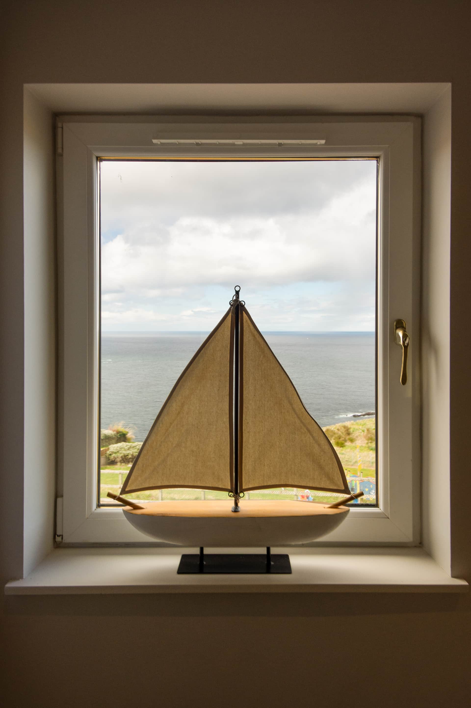 Model sailboat on the windowsill, sea beyond