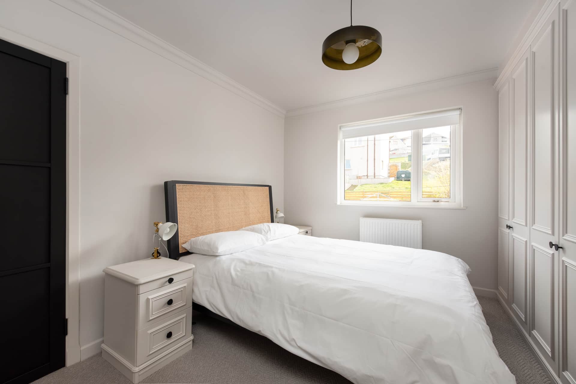 Bedroom with a rattan headboard and fitted wardrobes