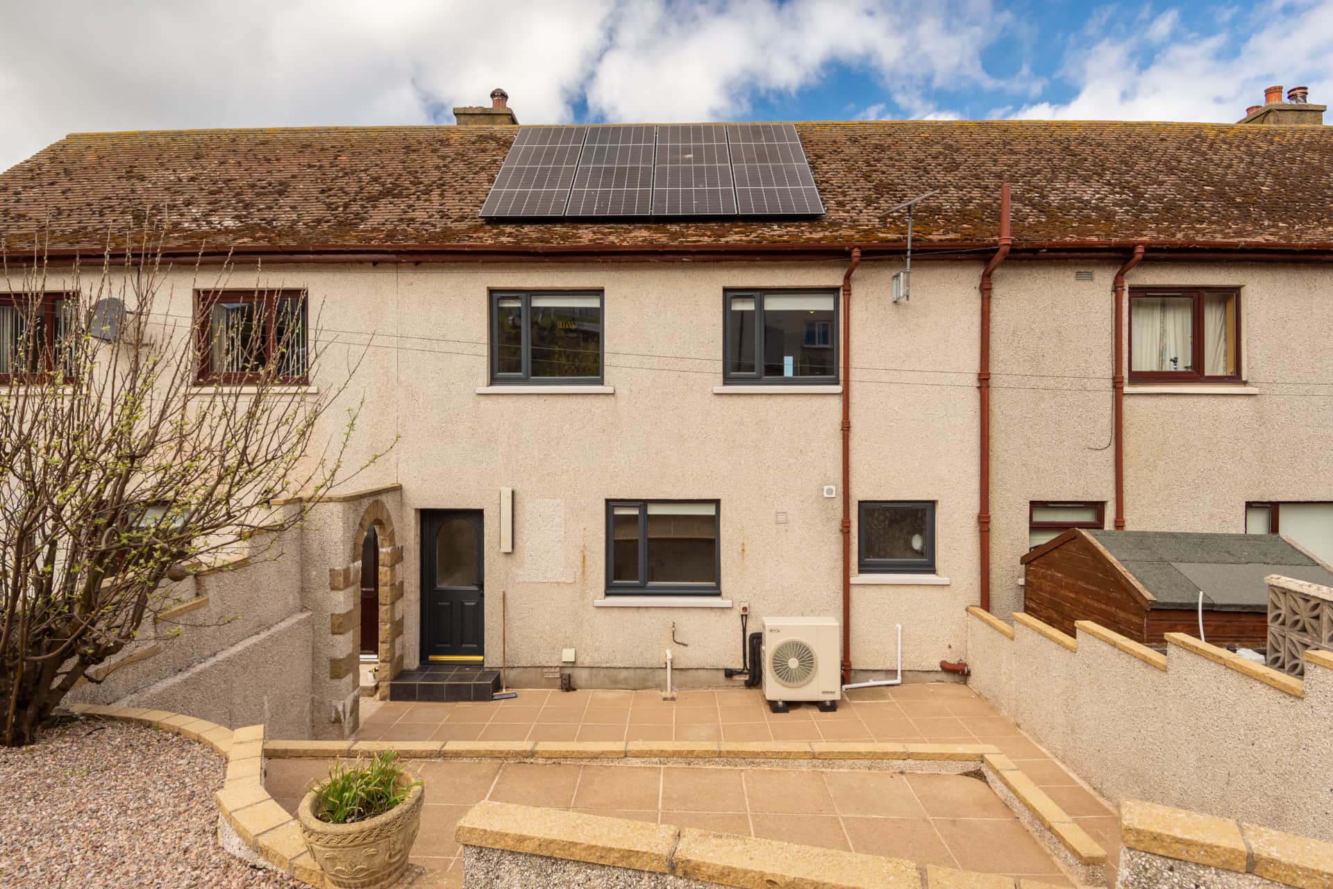 Rear exterior with solar panels and a paved patio