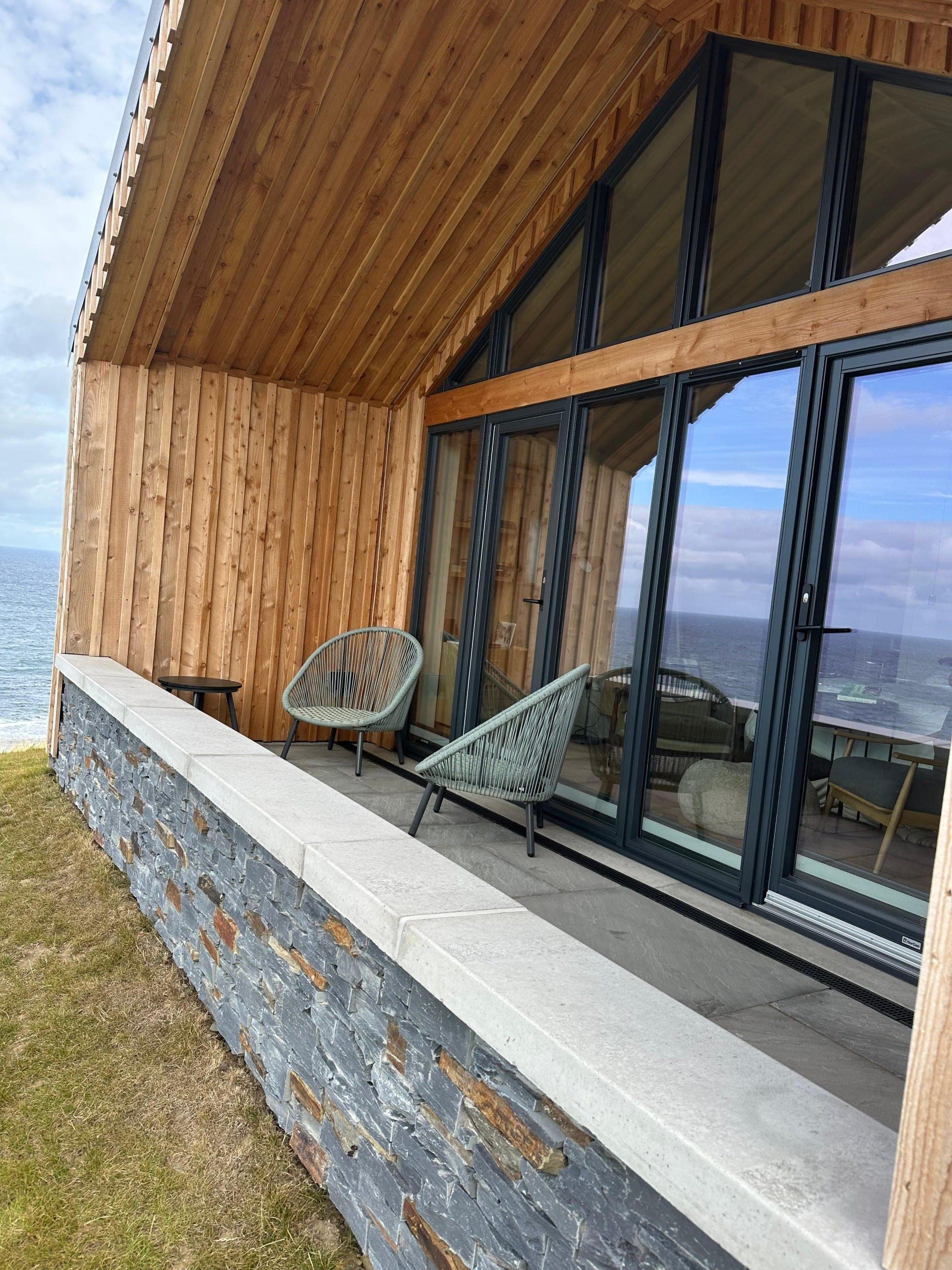 Muckle View's covered balcony with two chairs, looking out to sea