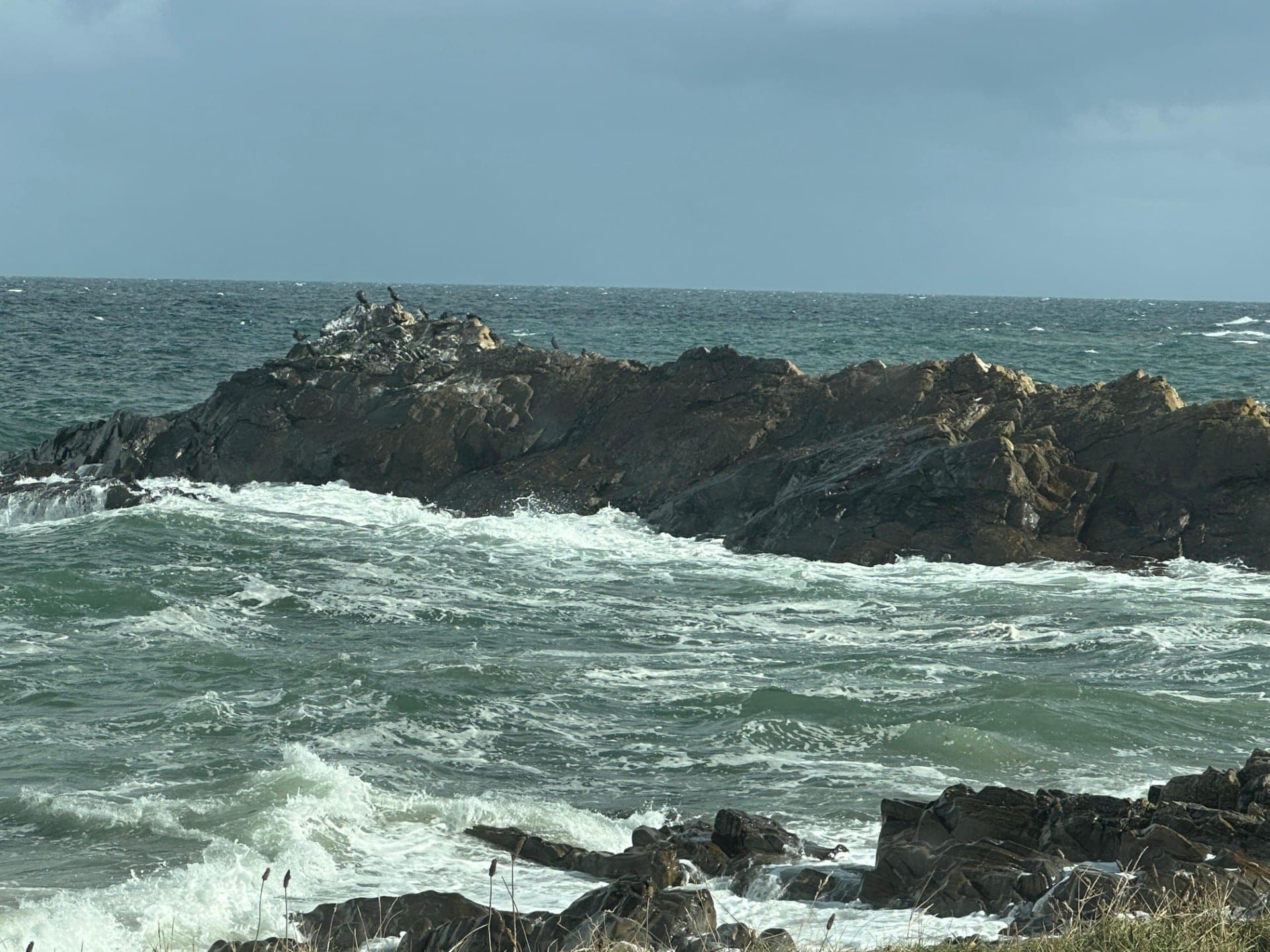 Waves breaking white over dark rocks on a stormy day on the Aberdeenshire coast